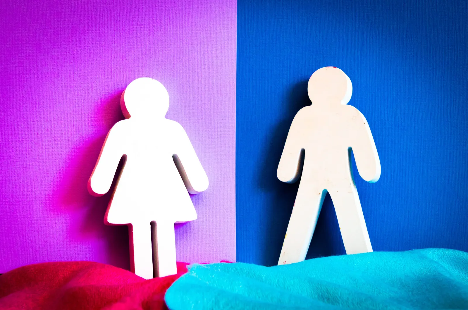 Two white cut-out figures, a woman in a dress and a man, against purple and blue backgrounds