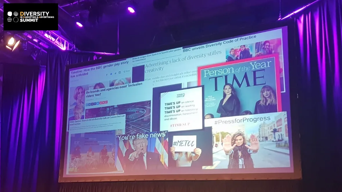 Screen on a stage at the Diversity in Marketing & Advertising Summit, showing news headlines and a TIME magazine cover