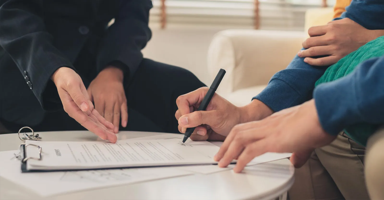 A person signs a document at a table while others observe, with the Aviva logo visible on the paper.