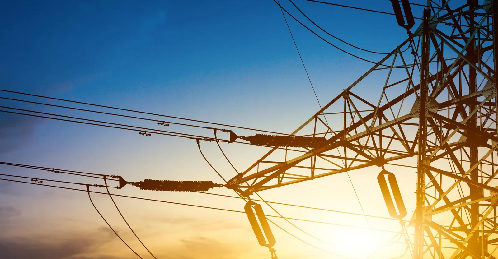 Electricity pylon and power lines silhouetted against a sunset sky