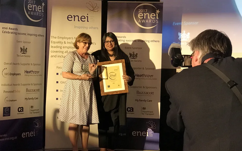 Two women holding a glass award and framed "Global Diversity Award" certificate at the 2017 enei Awards.