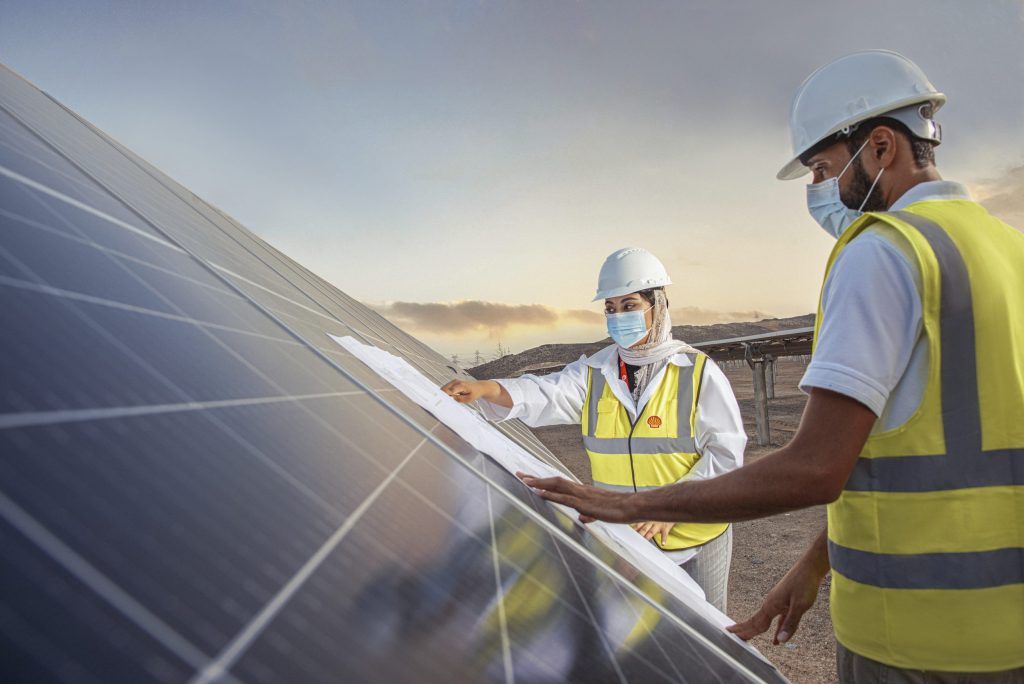 Two engineers in hard hats reviewing plans on a solar panel
