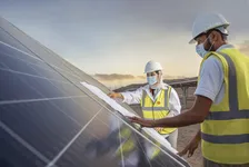 Two engineers in hard hats reviewing plans on a solar panel