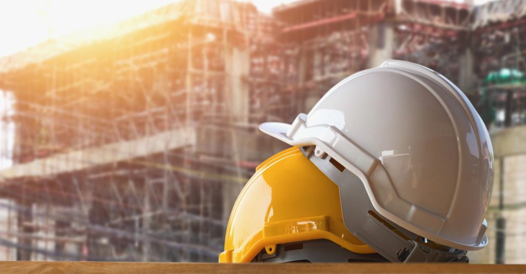White and yellow hard hats in front of a building under construction