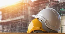 White and yellow hard hats in front of a building under construction